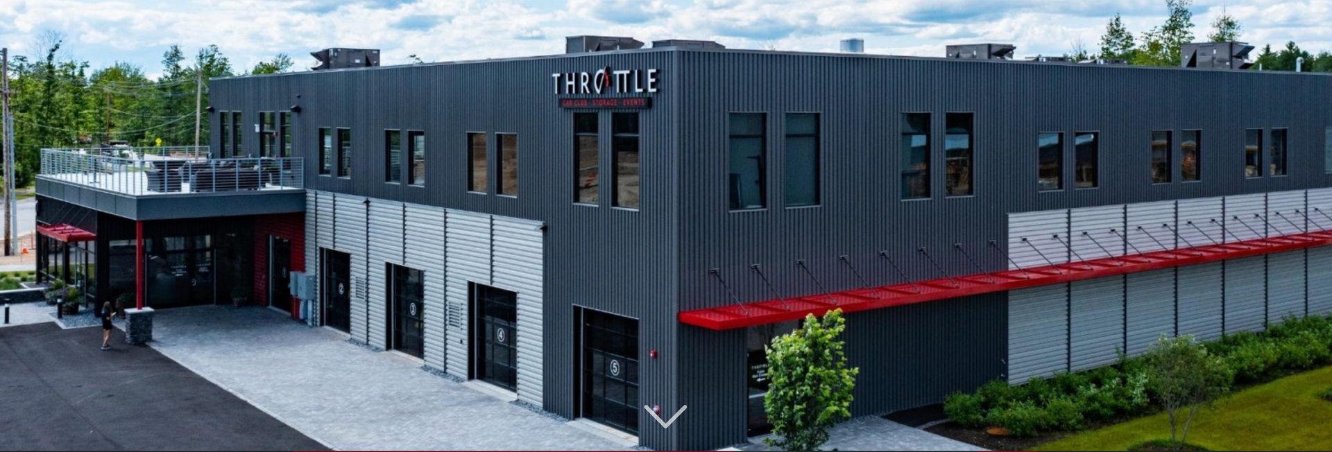 A large gray building with a lot of windows and a red awning.