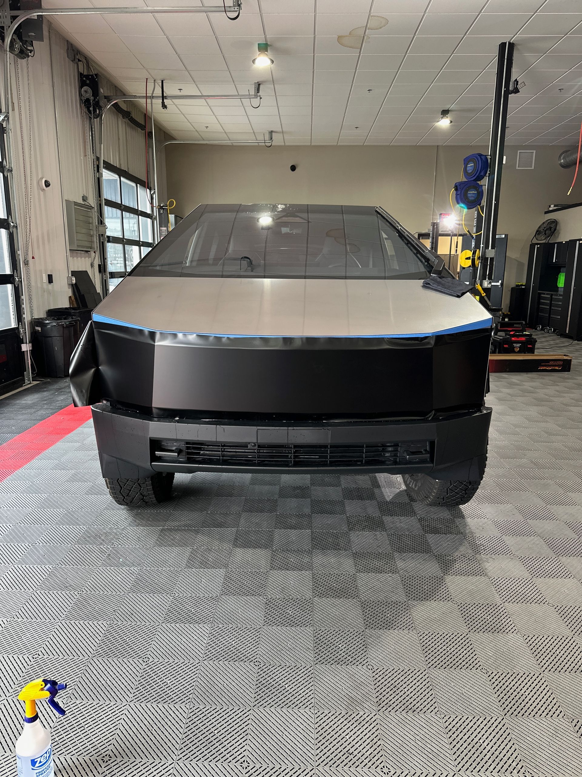 A black tesla cybertruck is parked in a garage.