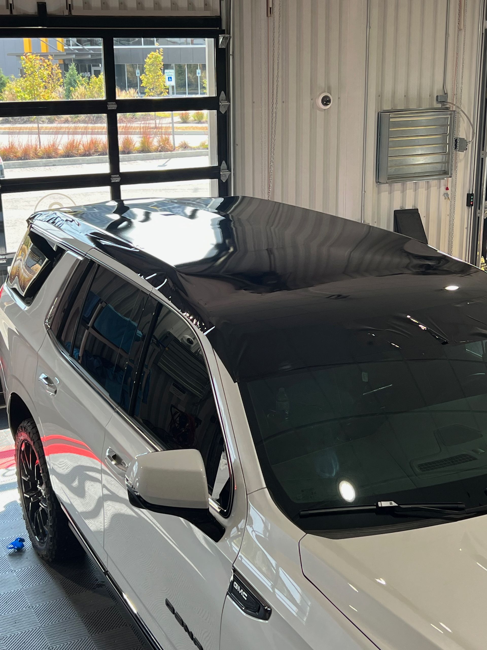 A white suv with a black roof is parked in a garage.