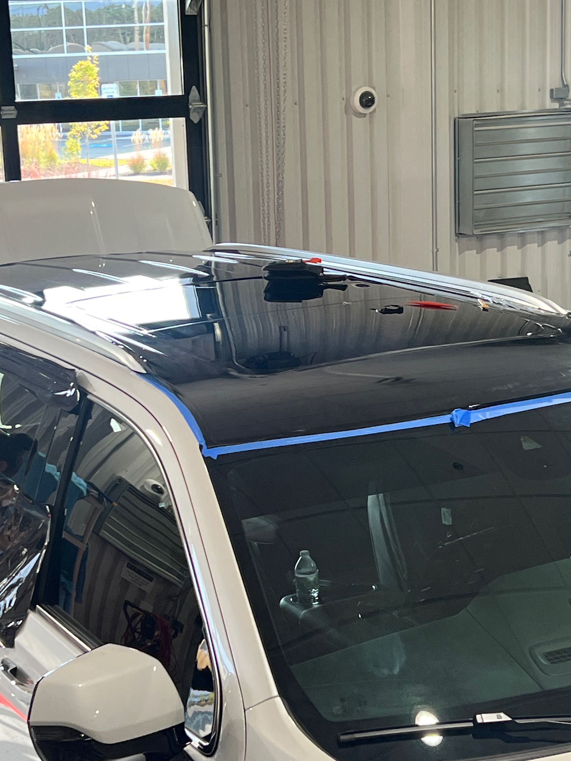 A white car with a black roof is parked in a garage