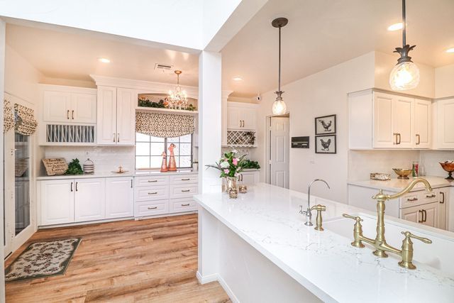 A kitchen with white cabinets , hardwood floors , a sink , and a window.