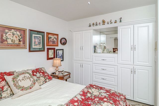 A bedroom with a bed , dresser , cabinets and a mirror.