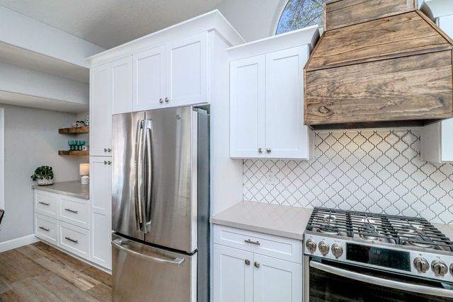 A kitchen with stainless steel appliances , white cabinets , a stove and a refrigerator.