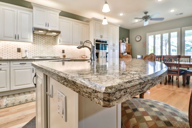 A kitchen with granite counter tops and white cabinets.