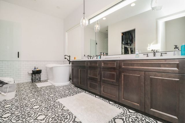 A bathroom with two sinks , a bathtub , and a large mirror.