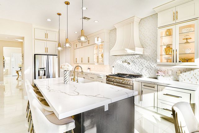 A kitchen with white cabinets , granite counter tops , stainless steel appliances and a large island.