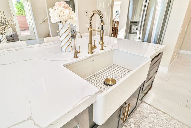A kitchen sink with a vase of flowers on top of it.