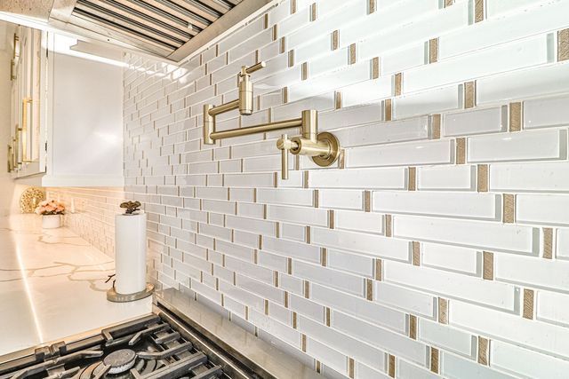 A kitchen with white tiles and a stove top oven.