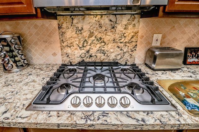 A stove top oven is sitting on top of a granite counter in a kitchen.