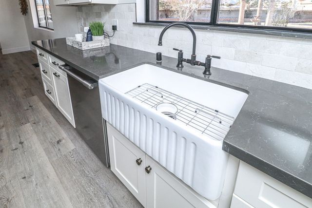 A kitchen with a large white sink and a black faucet.