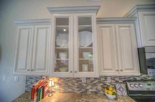 A kitchen with white cabinets , granite counter tops , a stove and a sink.