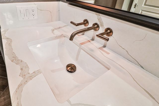 A bathroom sink with two faucets and a mirror.