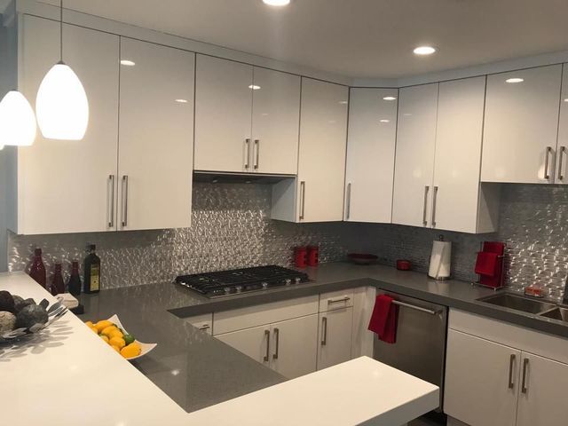 A kitchen with white cabinets and a stove top oven
