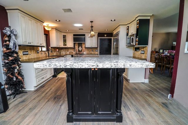 A kitchen with a large island and a christmas tree in the background.