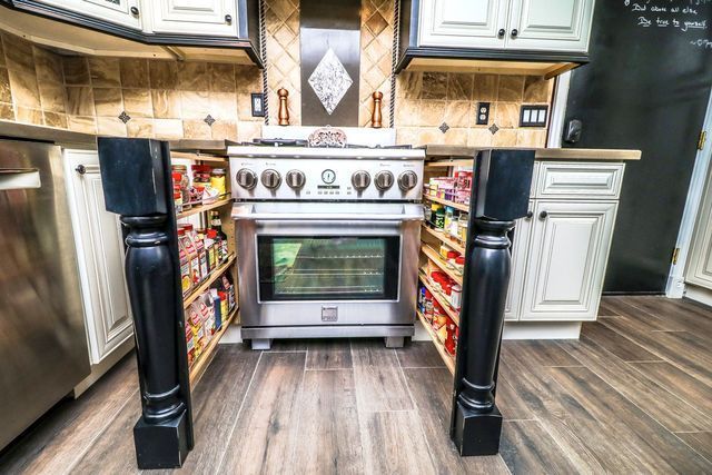 A kitchen with a stove and a pantry underneath it.