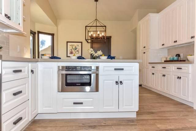 A kitchen with white cabinets , stainless steel appliances , and a large island.