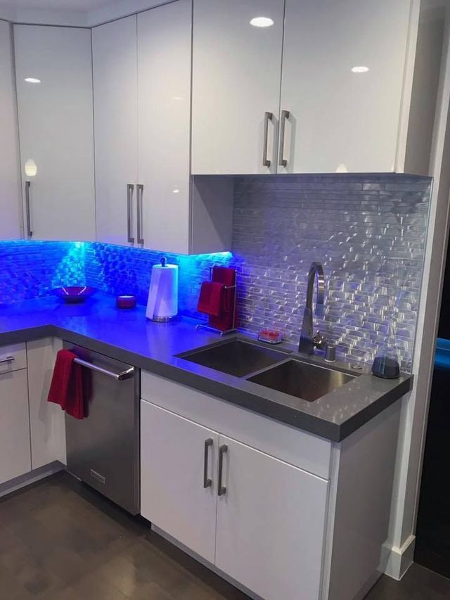 A kitchen with white cabinets and a stainless steel sink.