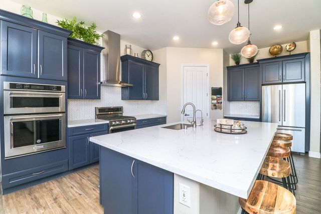 A kitchen with blue cabinets , white counter tops , stainless steel appliances and a large island.