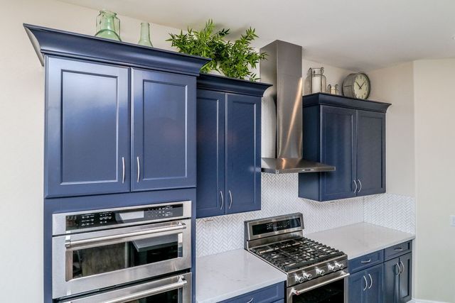 A kitchen with blue cabinets and stainless steel appliances.