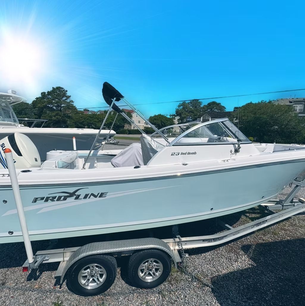 A white Pro-Line boat on a trailer under a blue sky.