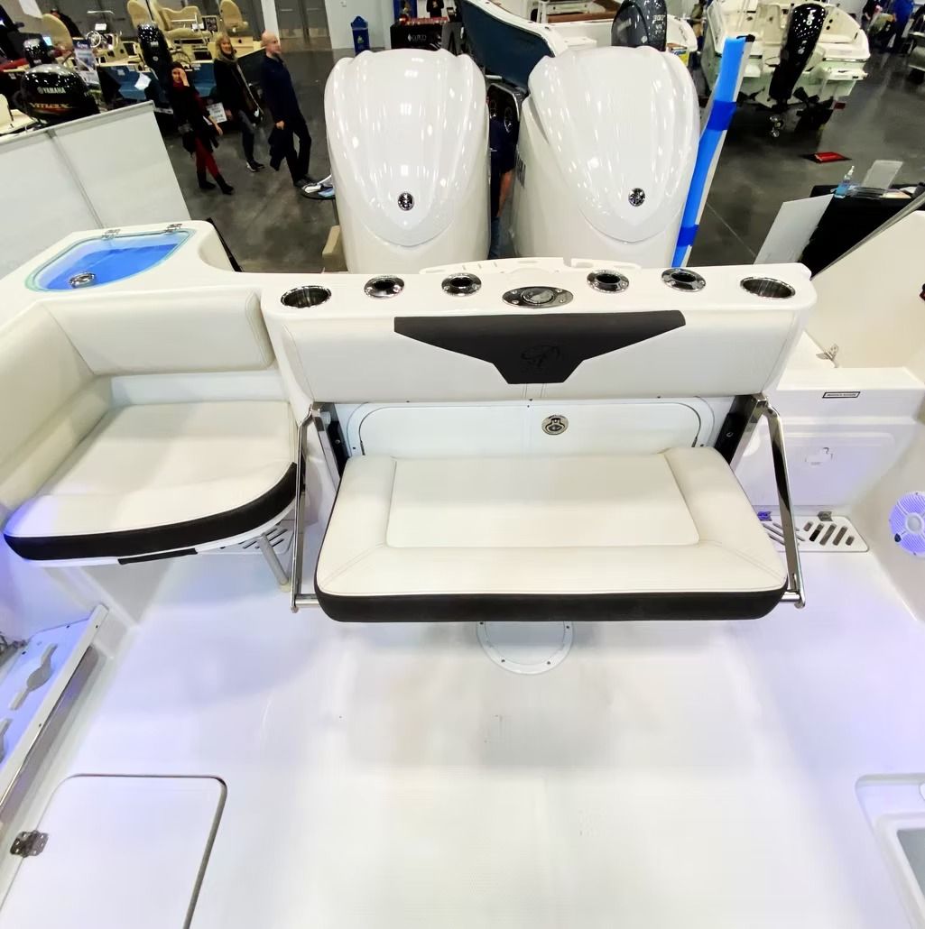 A boat's white rear deck with fold-down seat, cup holders, and two outboard engines.