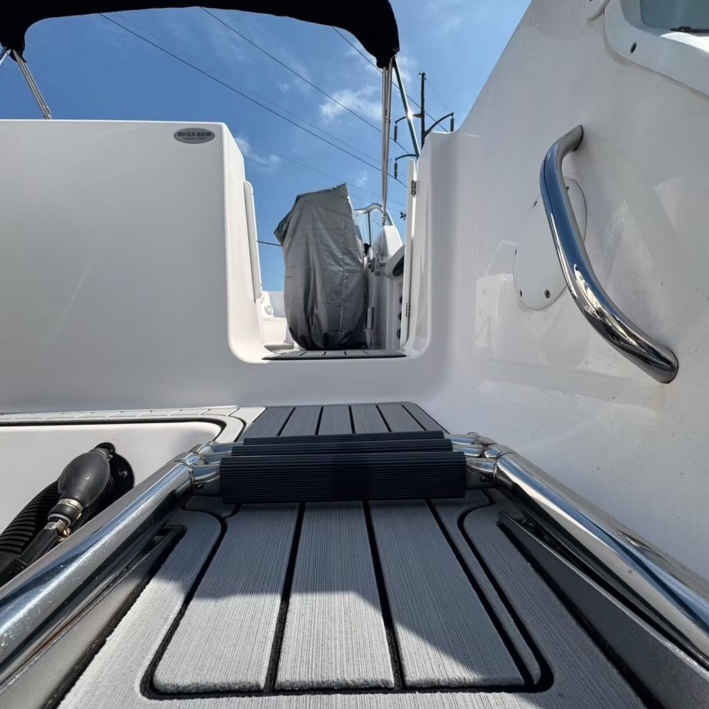 A boat's interior with gray and white flooring and a view towards the covered steering area.