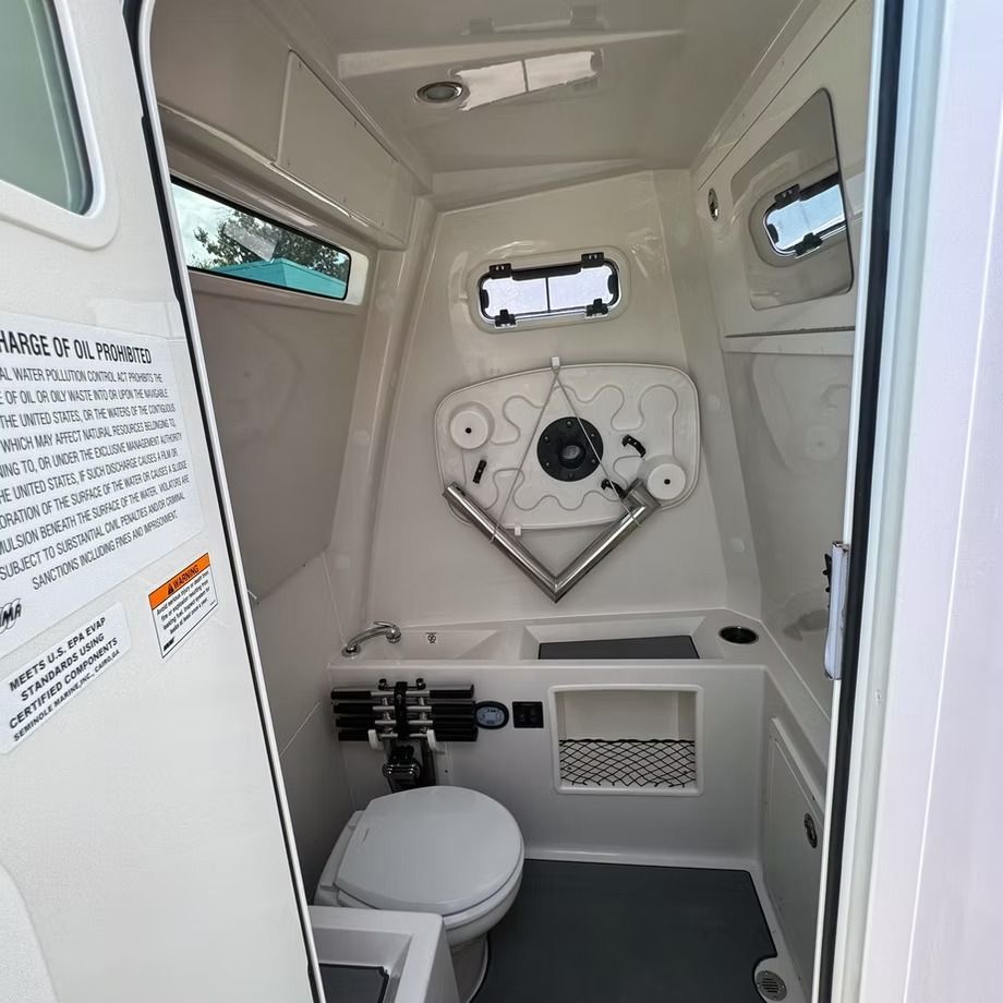 Interior of a small boat bathroom, white walls, toilet, sink, and storage.