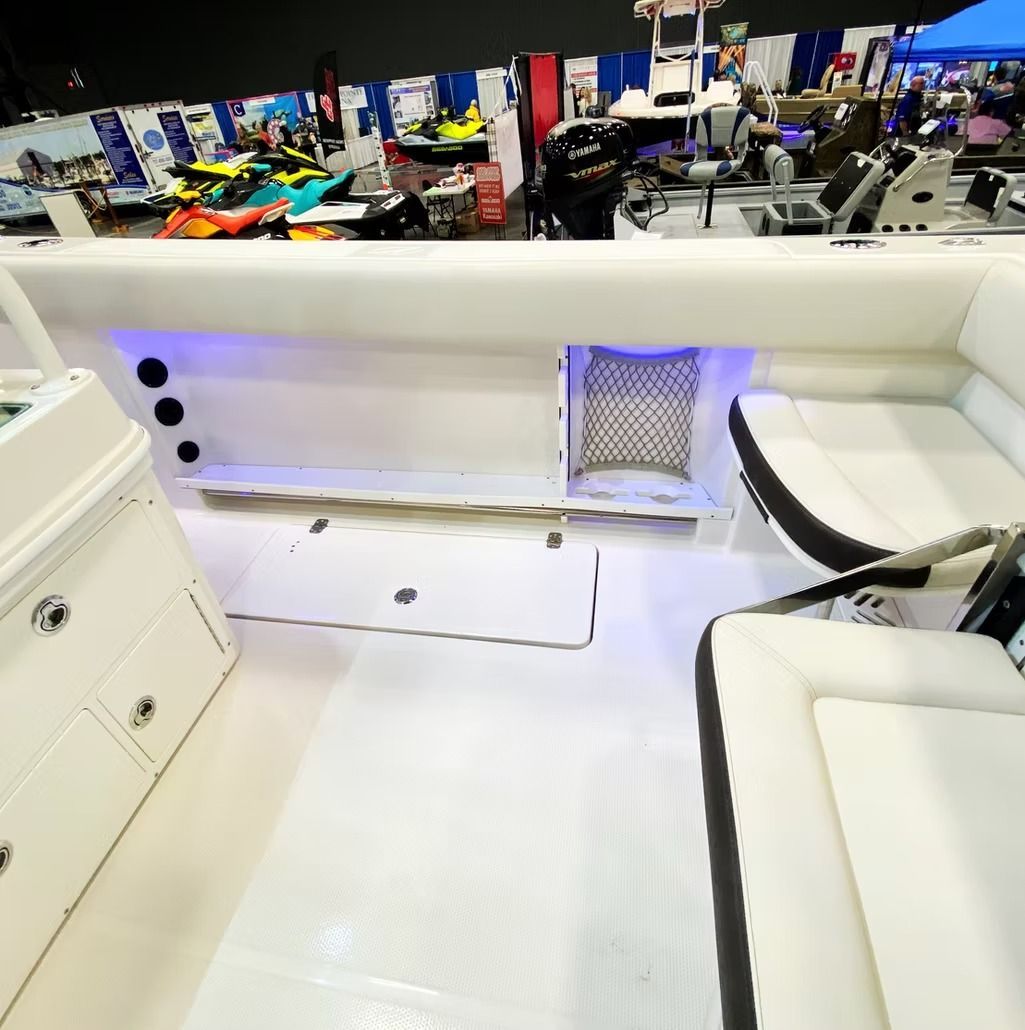 Boat interior with white flooring and seating, featuring storage and blue accent lighting.