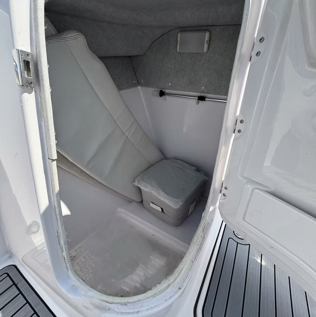 Open storage compartment in a white boat; cushioned seat and small cooler inside.