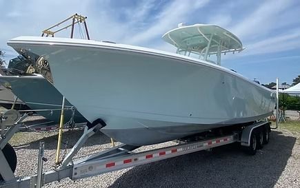 Light blue boat on a trailer, in an outdoor setting. White hardtop, gray hull.