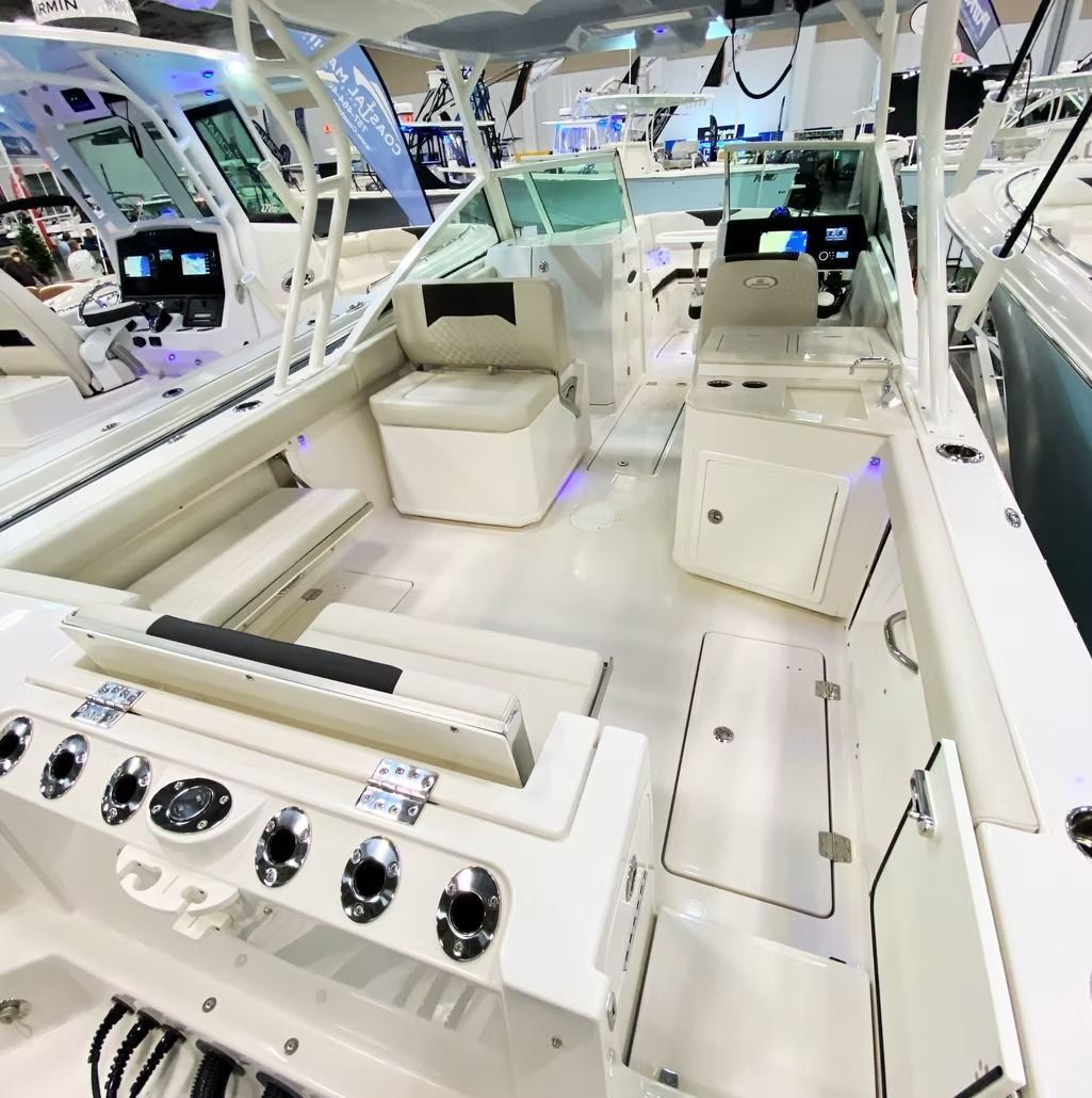 Interior of a white boat with seats and dashboard, likely at a boat show.
