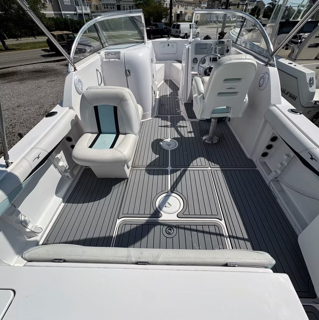 White fishing boat interior with gray flooring, two seats, and a windshield.