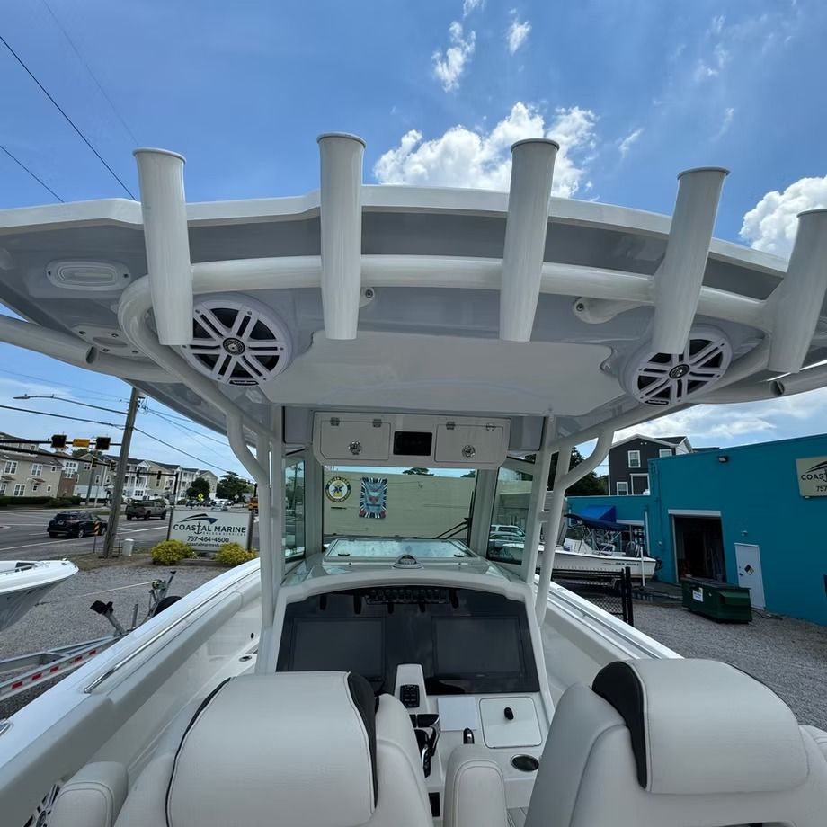 Interior view of a white boat cabin, with fishing rod holders and speakers on the roof.