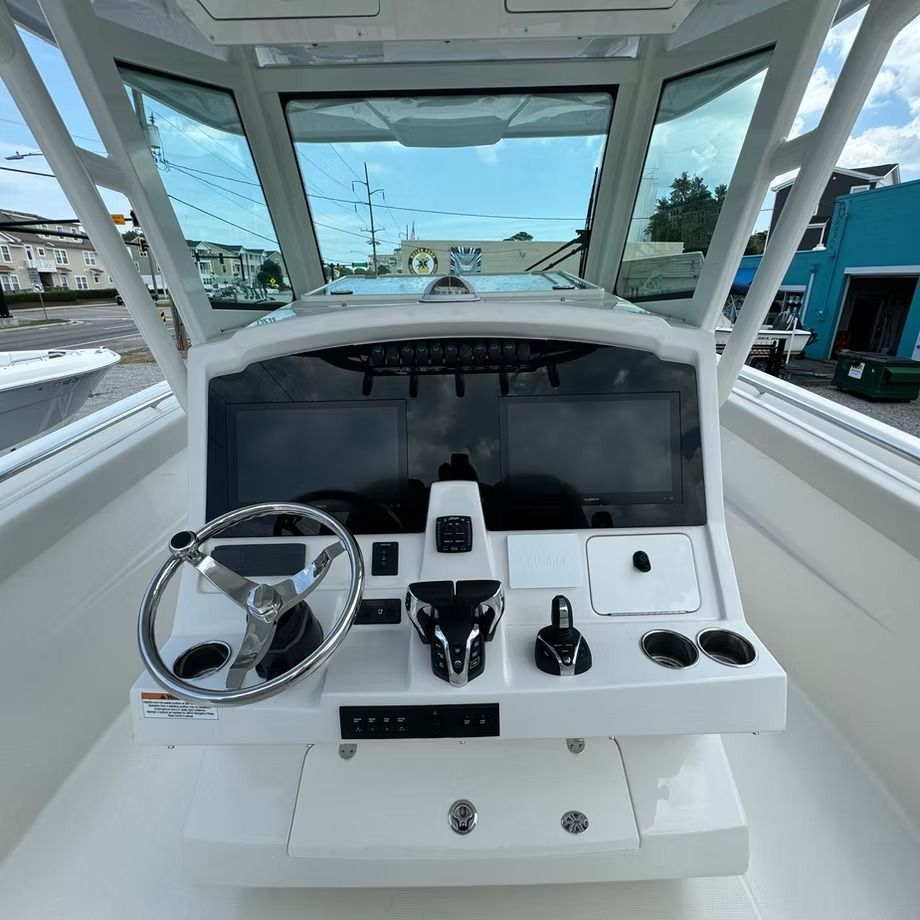 Boat dashboard with steering wheel, display screens, and controls. Bright, daytime setting.