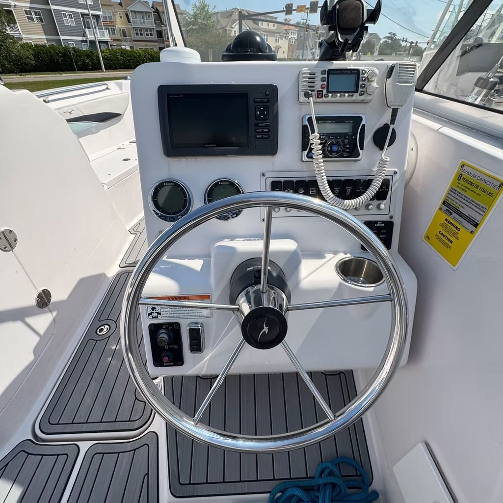 Boat's helm with steering wheel, navigation electronics, and gauges.