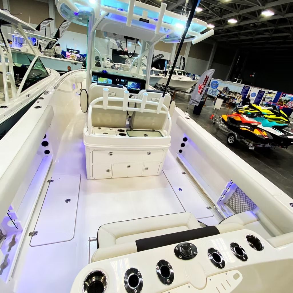 White fishing boat interior with seating, navigation, and rod holders, in a showroom setting.