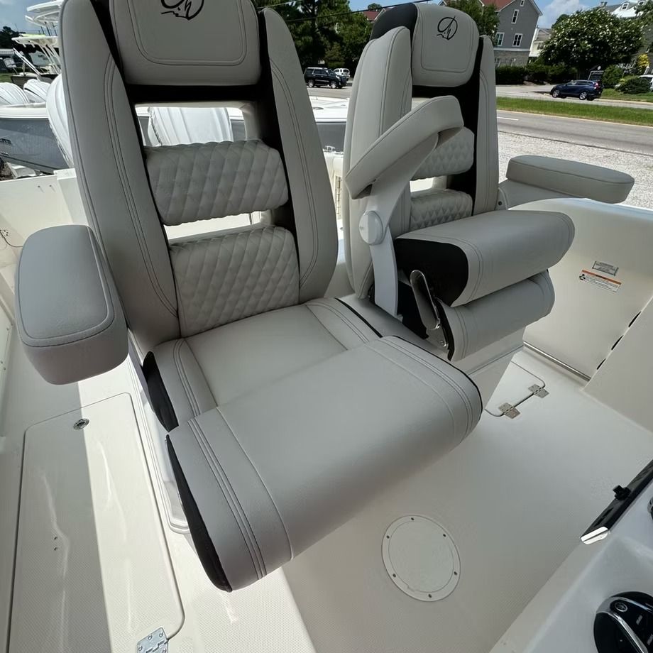 Two white and gray boat captain's chairs with armrests. Outdoor setting.