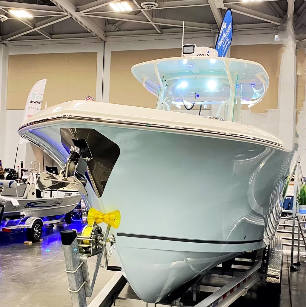 Light blue boat on a trailer inside a building, with lights on.