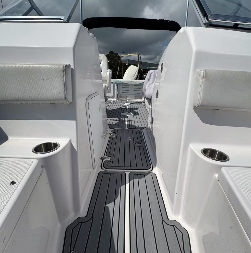 Boat interior with gray flooring, white walls, cup holders, and a view to the outside.