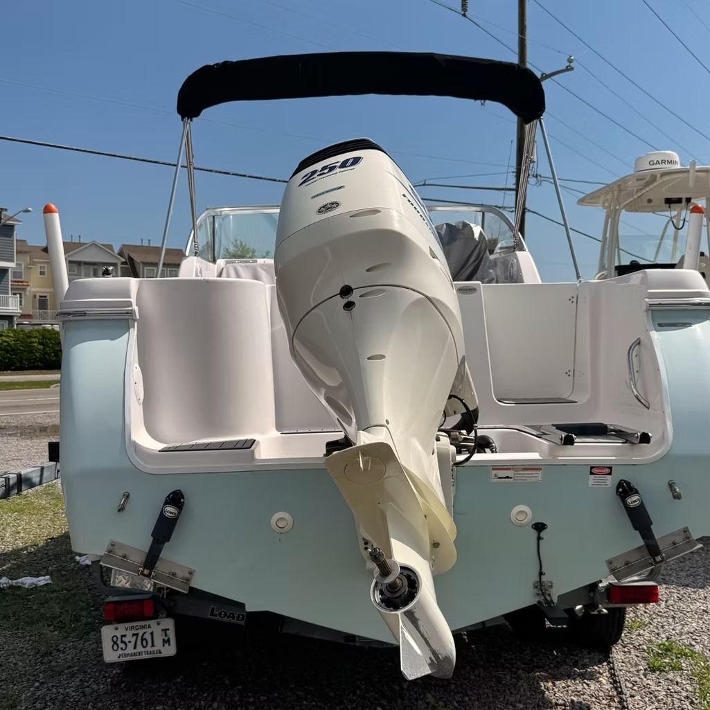 Rear view of a light blue motorboat with a white engine, parked outside.