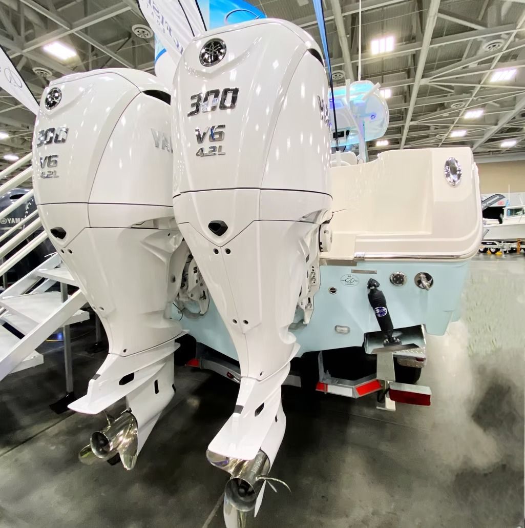 Two white Yamaha 300hp outboard motors on a boat. The boat is pale blue and white, in a showroom.