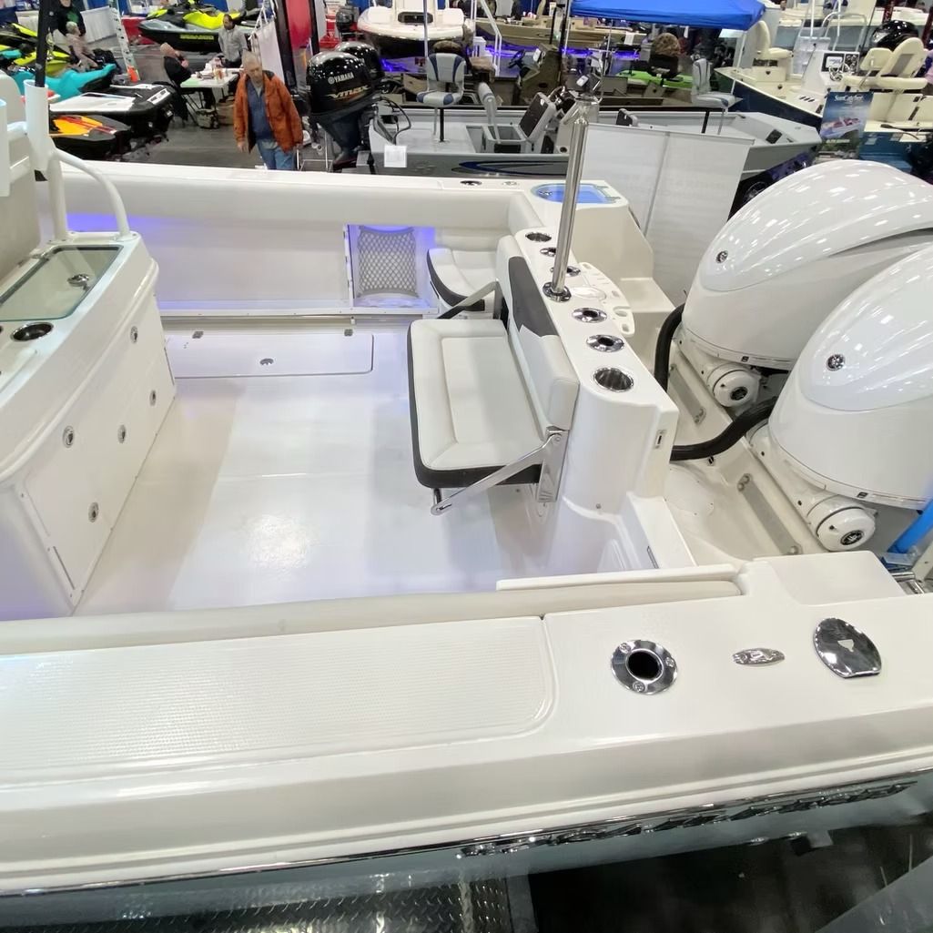 White motorboat with two large outboard motors, on display at a boat show.