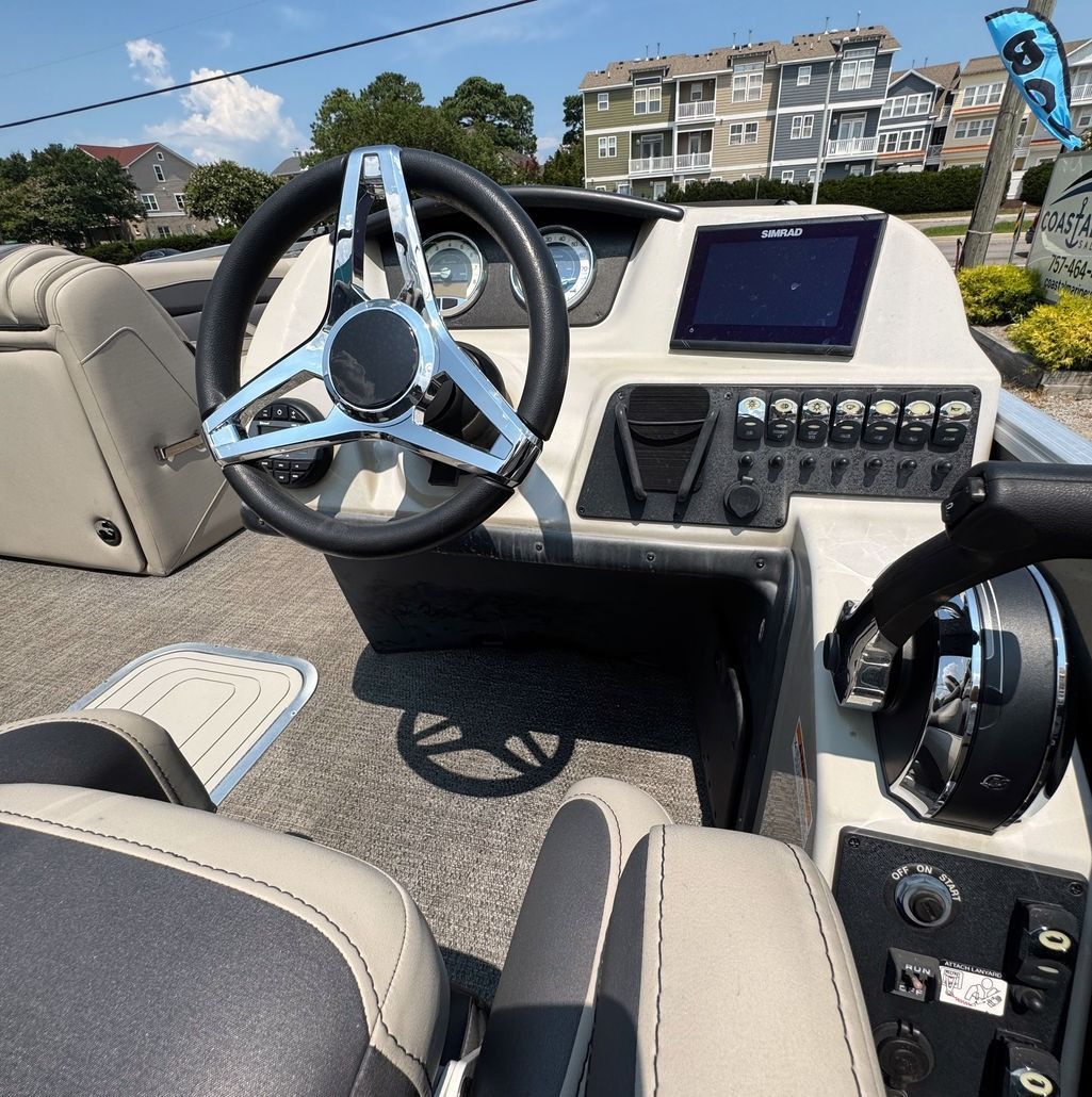 Boat dashboard with silver steering wheel, navigation screen, and grey seats.