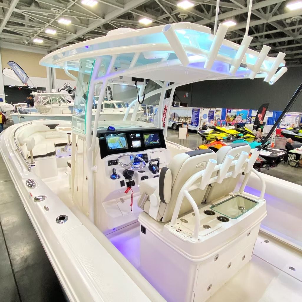 White center console boat at an indoor boat show with a clear roof and blue lighting.