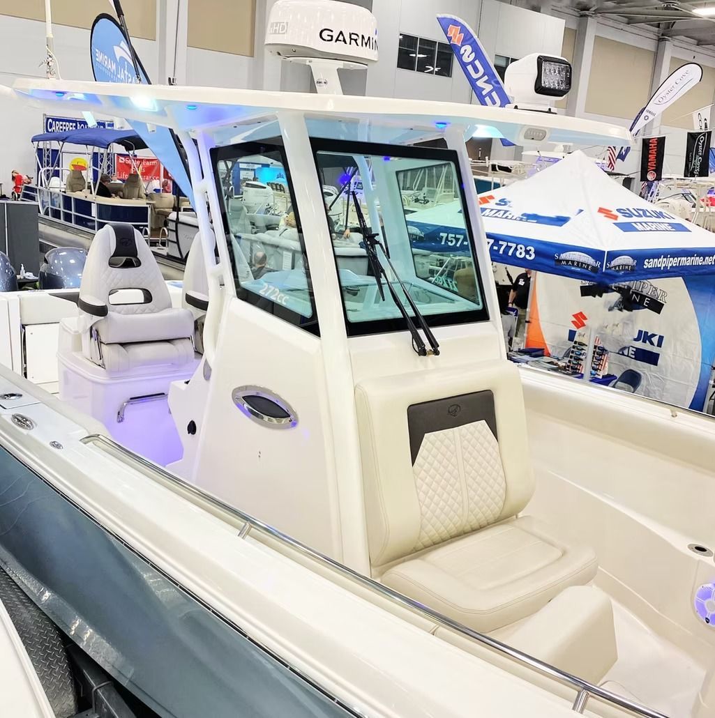 White boat with a cabin, at a boat show, with blue lighting and seating.
