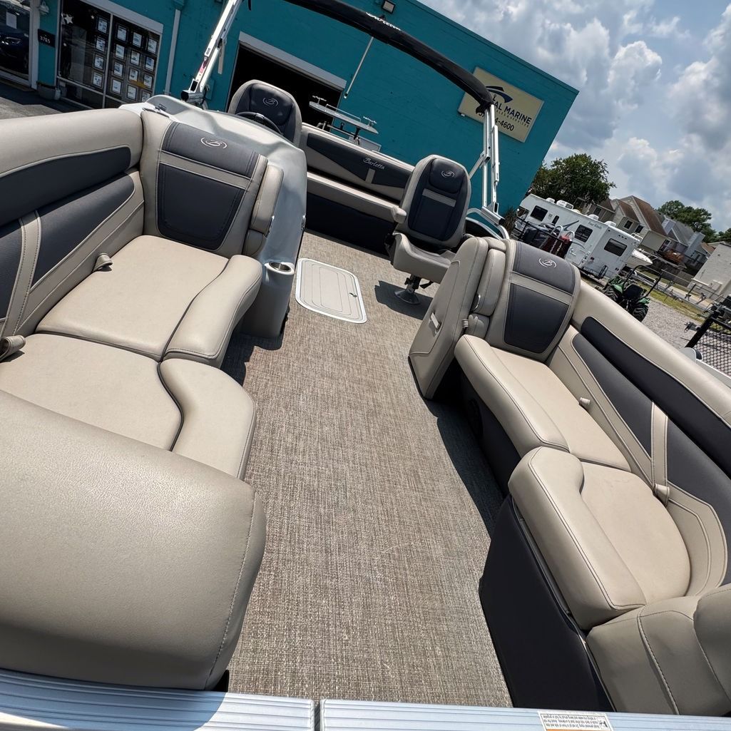 Pontoon boat interior with beige and gray seating, under a bright blue sky.