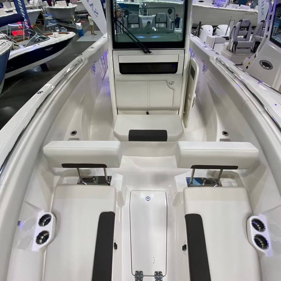 Interior of a white motorboat with seating, cup holders, and a windshield.