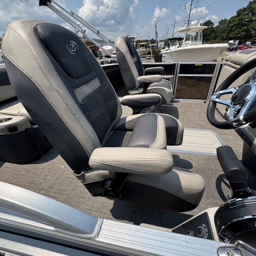 Boat interior with gray and white seats, steering wheel.