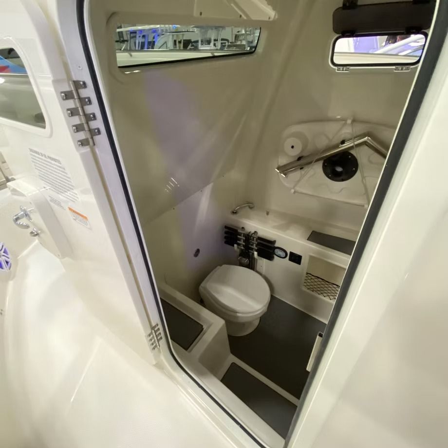 Boat cabin with a toilet, sink, and storage. White interior with gray floor.