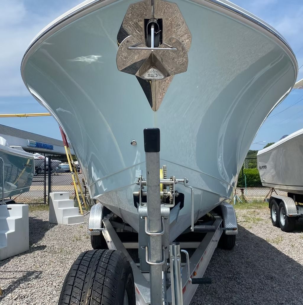 A light blue boat on a trailer, seen from the front, outdoors.